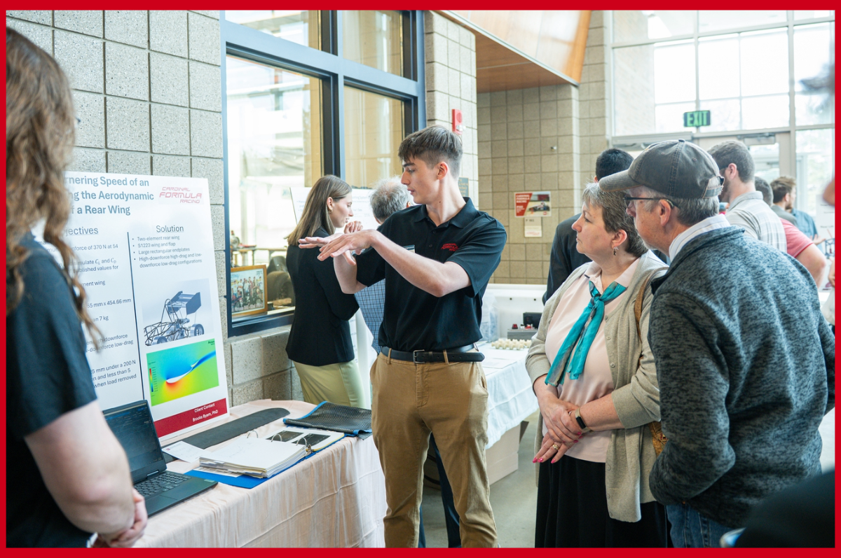 Student looks at presentation board while explaining project to onlookers